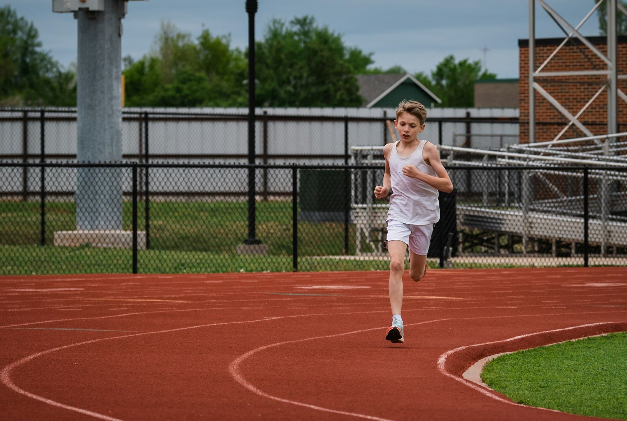 A young preteen boy running track and field