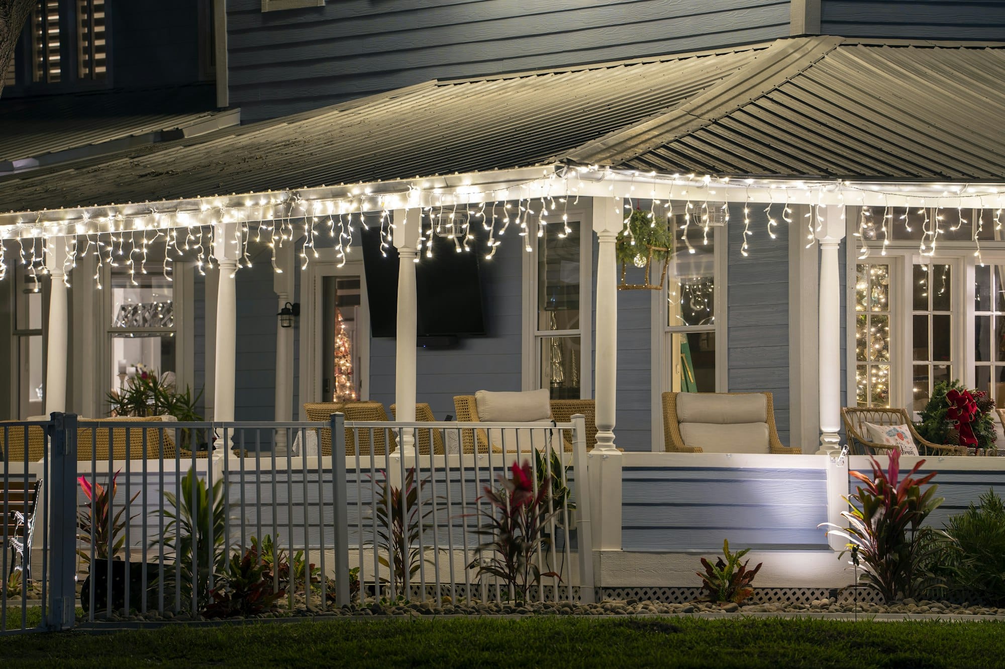 Patio delantero de la casa con gran porche iluminado con adornos navideños.